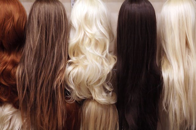 Image of seven wigs of different hair colors.