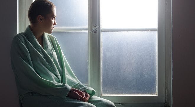 Image of a woman wearing a mint-colored bathrobe, staring out the window.