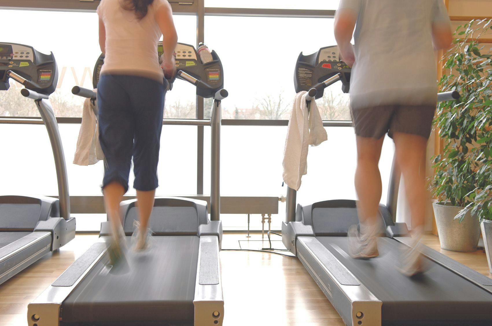 Two side-by-side treadmills with people walking on them