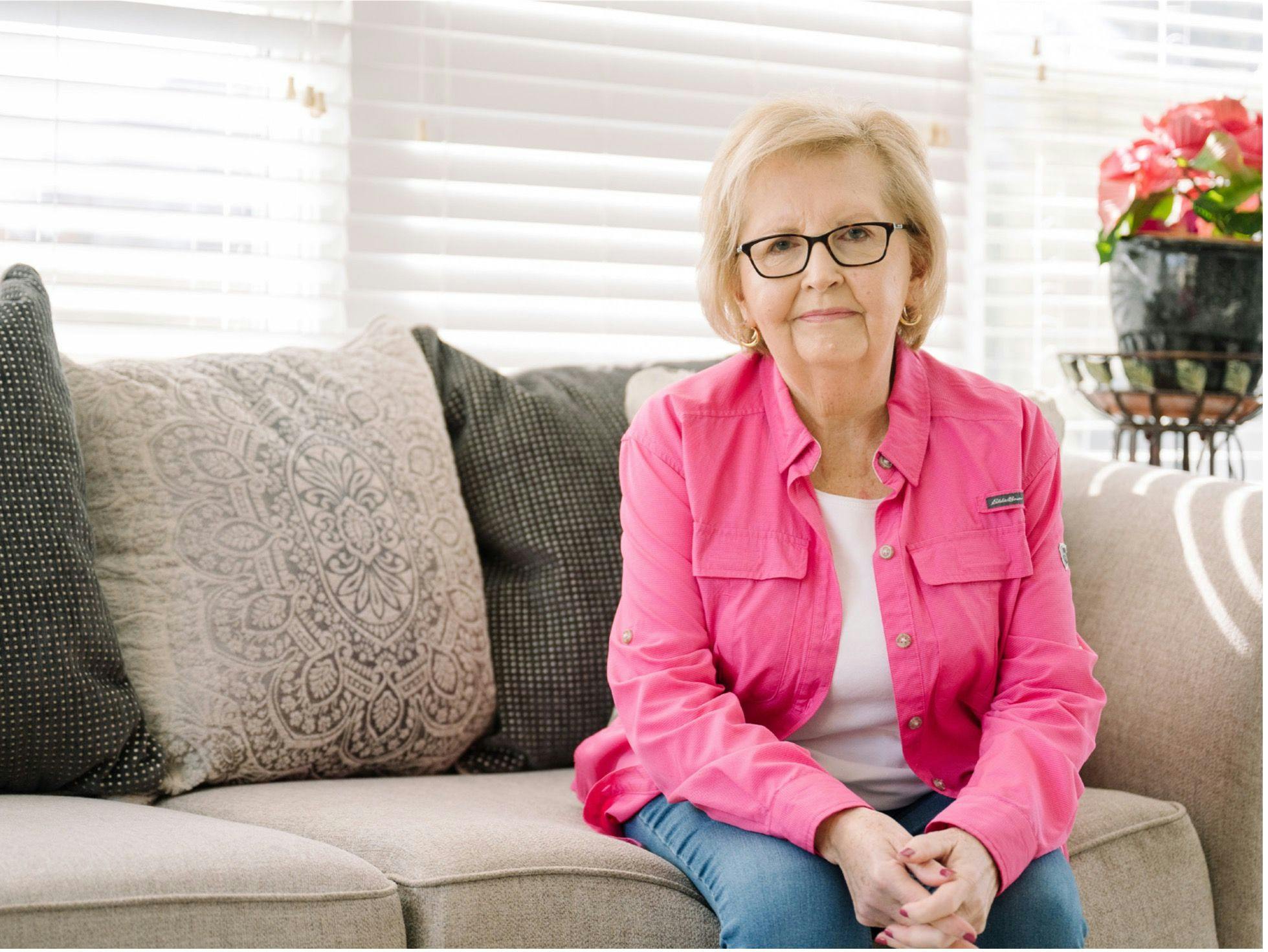 Brenda Duggins sitting on the couch, wearing a pink shirt