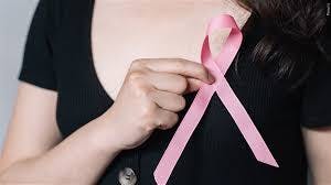 Image of a woman with a black t-shirt holding a pink ribbon over her breast.