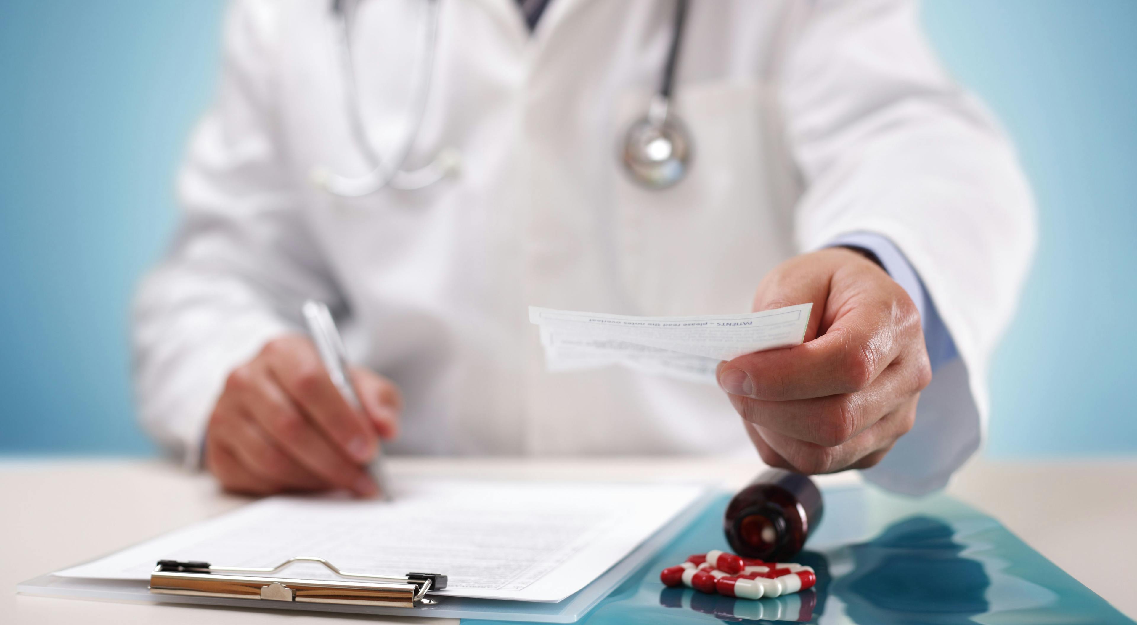 physician in a white coat handing a prescription