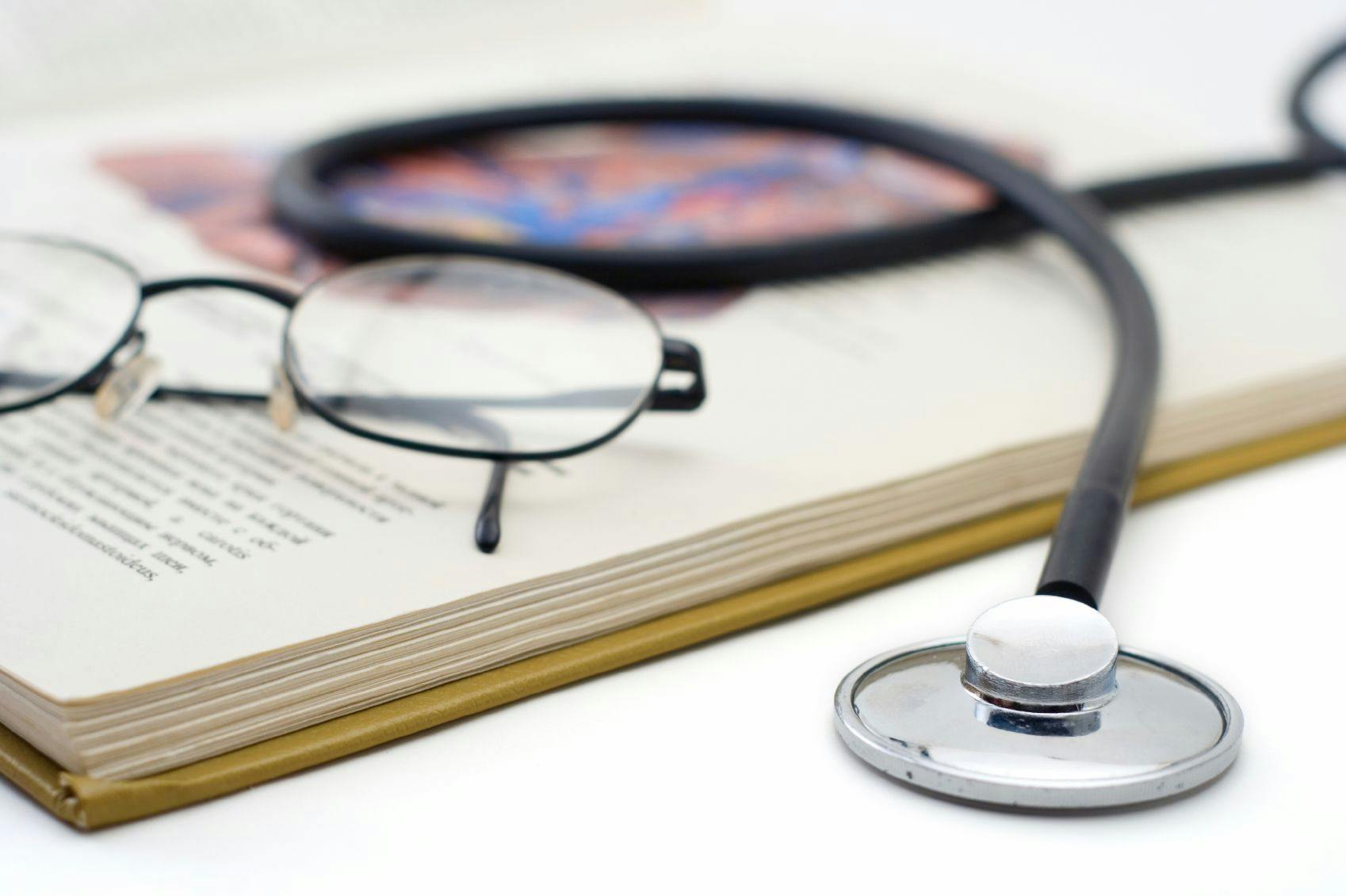 glasses and a stethoscope placed on a textbook