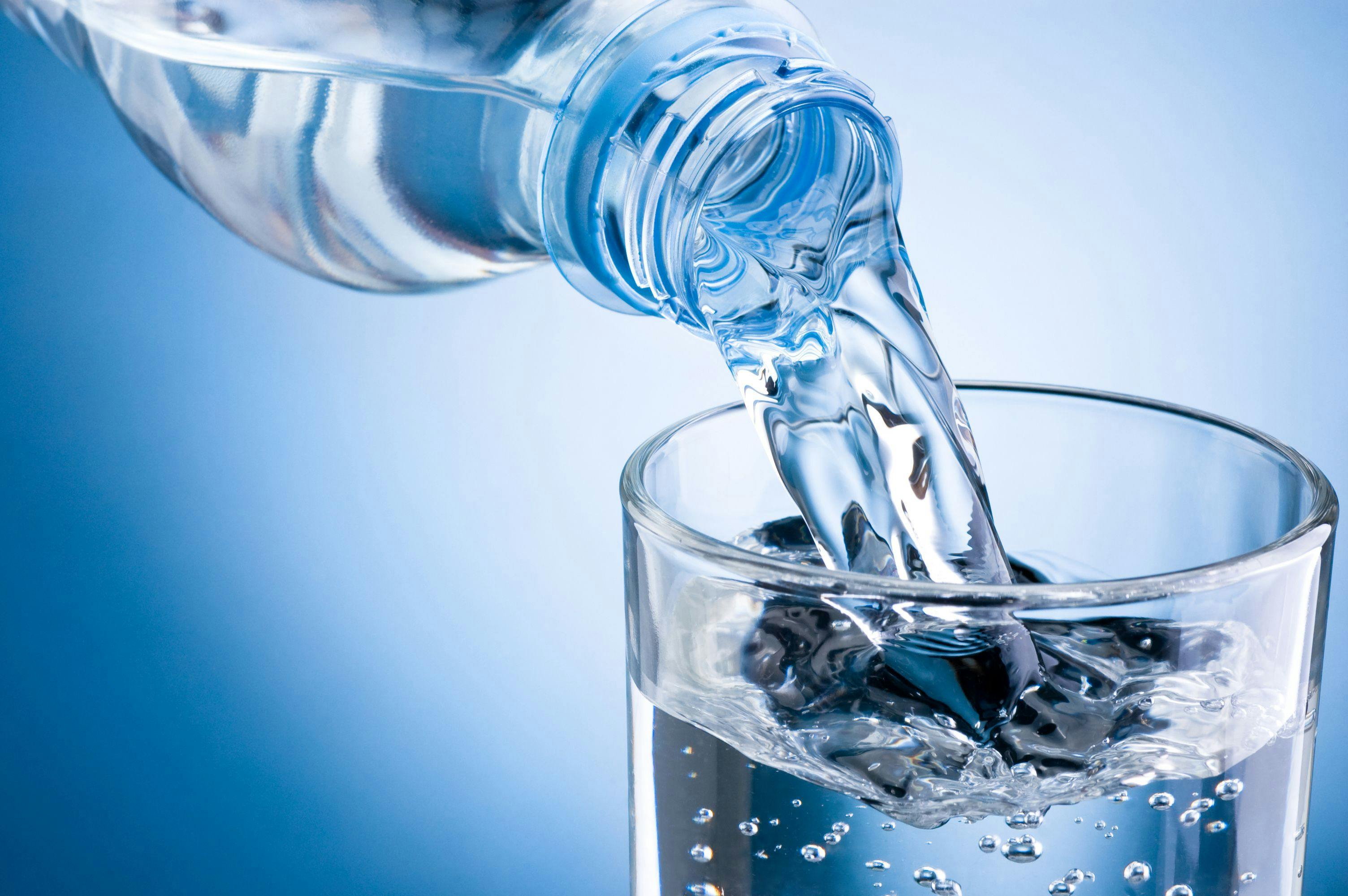 Pouring water from bottle into glass on blue background | Image credit: © Hyrma stock.adobe.com
