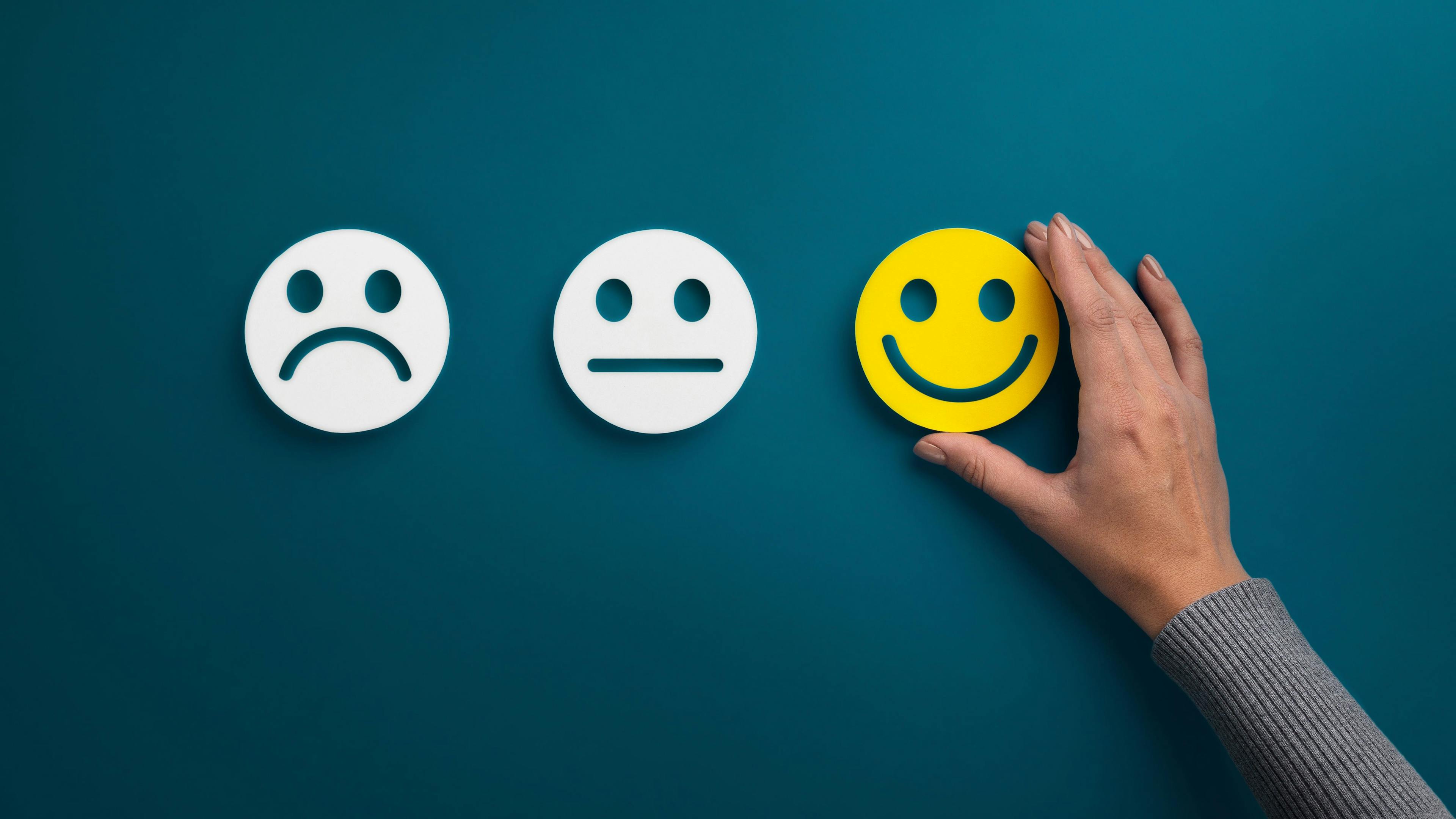 Three emojis: two white sad emojis, and a smiling emoji