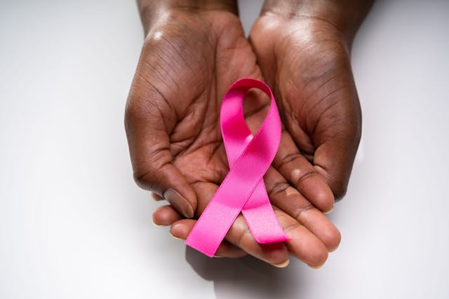 African American hands holding a pink breast cancer ribbon