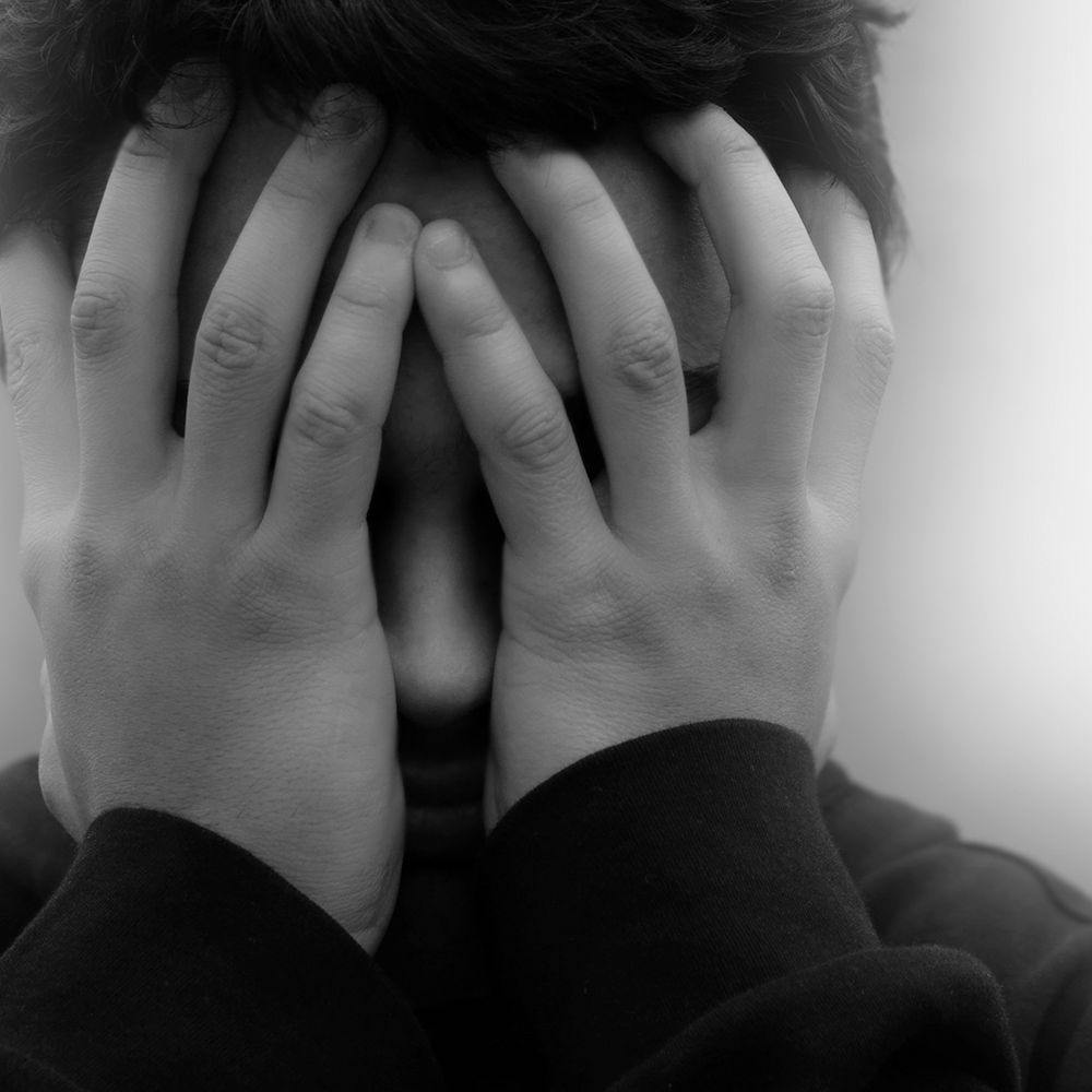 black and white image of stressed person putting their hands on their face