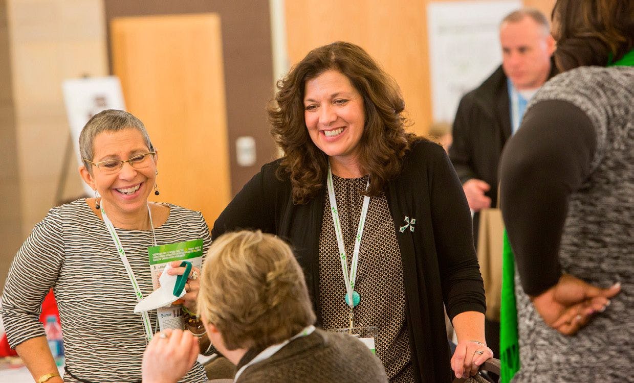 “MELINDA BACHINI (center), whose cholangiocarcinoma has responded to immunotherapy, mingles with attendees at the Cholangiocarcinoma FoundationAnnual Conference. PHOTO BY BARR PHOTOGRAPHY (COURTESY OFTHE CHOLANGIOCARCINOMA FOUNDATION”