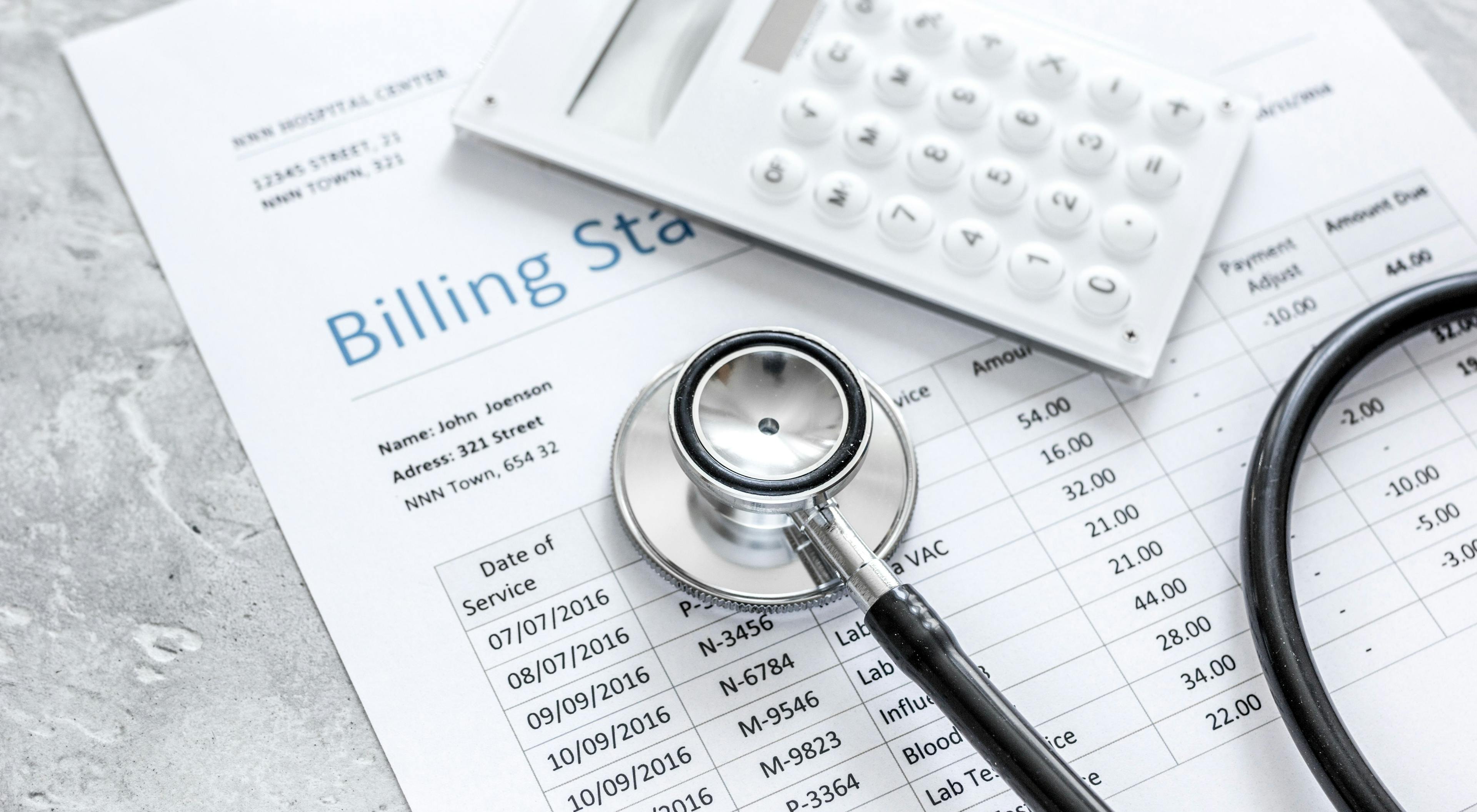 A stethoscope and calculator over a medical billing statement