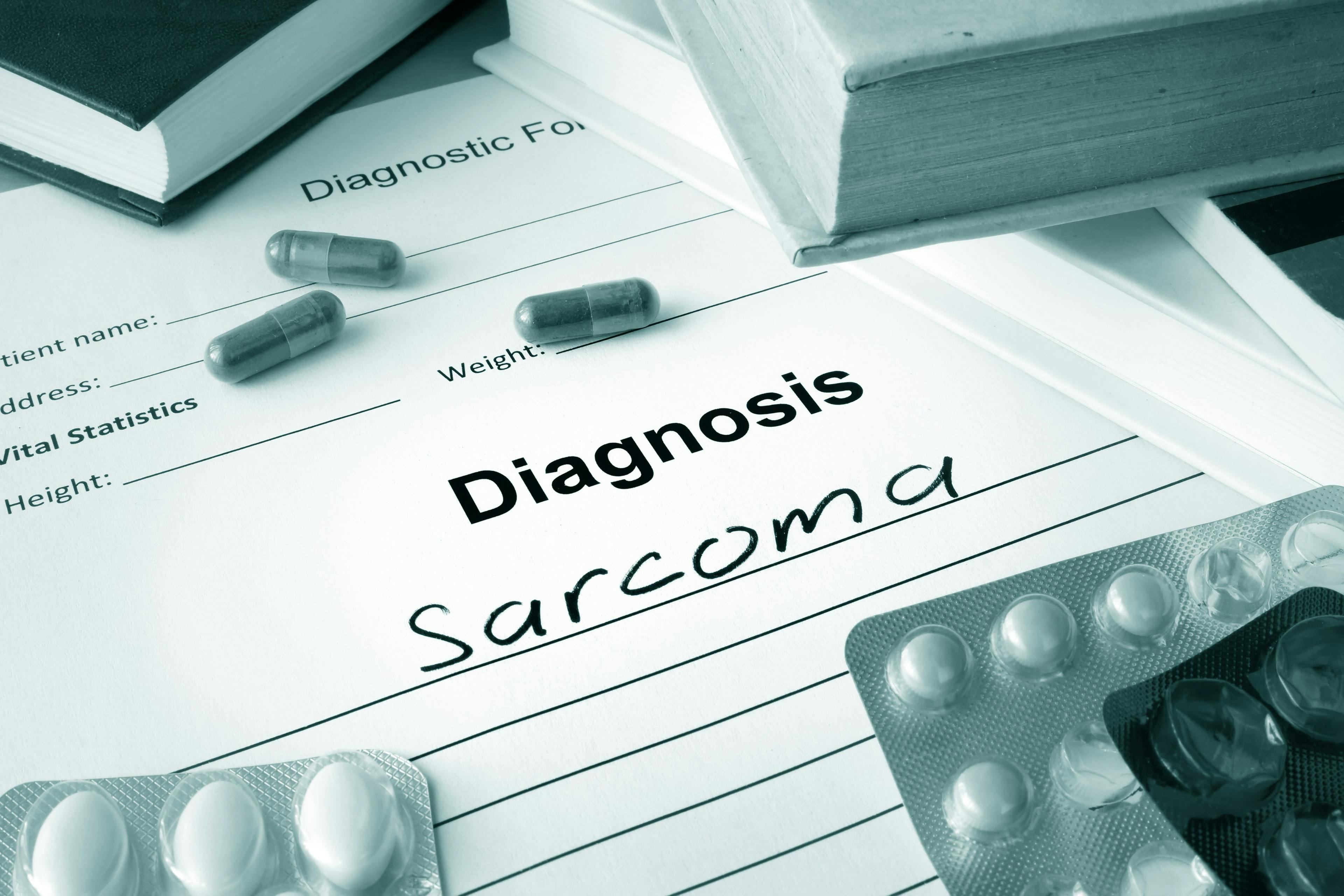black-and-white image of a diagnosis pad with the words "Diagnosis sarcoma" written on it. Pills surround the writing