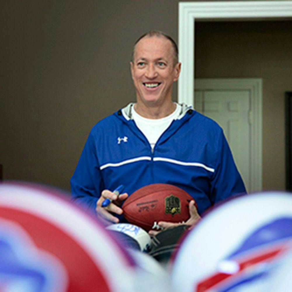 NFL player, Jim Kelly, holds a ball and smiles