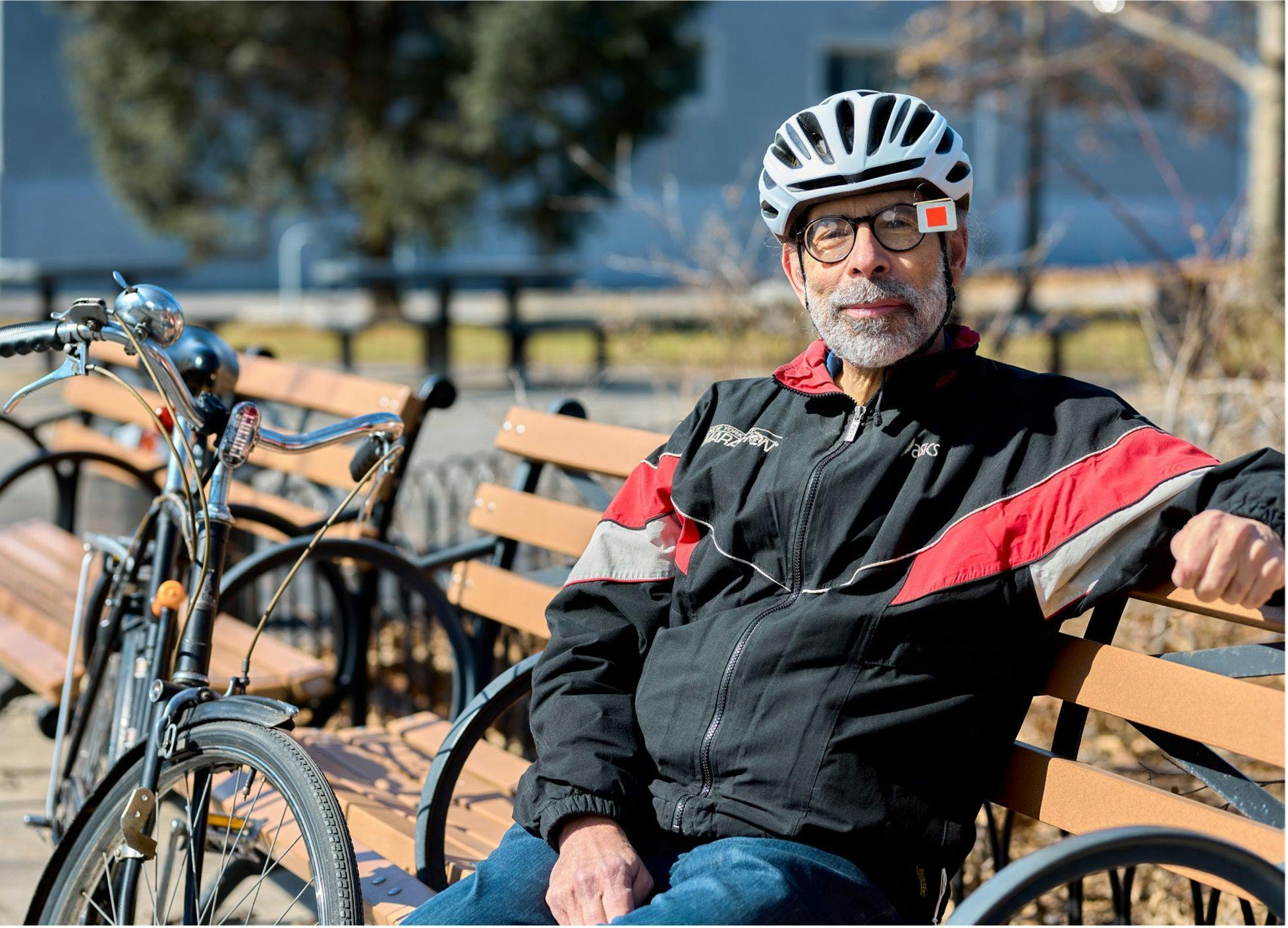 MPN Survivor, David Alexander wearing a bike helmet, sitting on a bench next to his bike. | Photo by Agne Sopyte