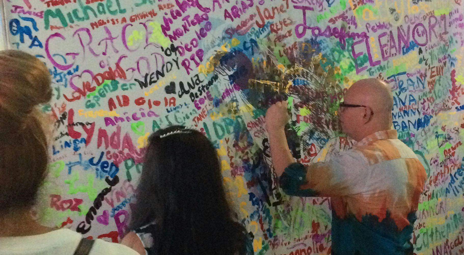 Attendees at the Life and Liberty event paint their names on a mural that will be displayed at John Theurer Cancer Center for the next year.