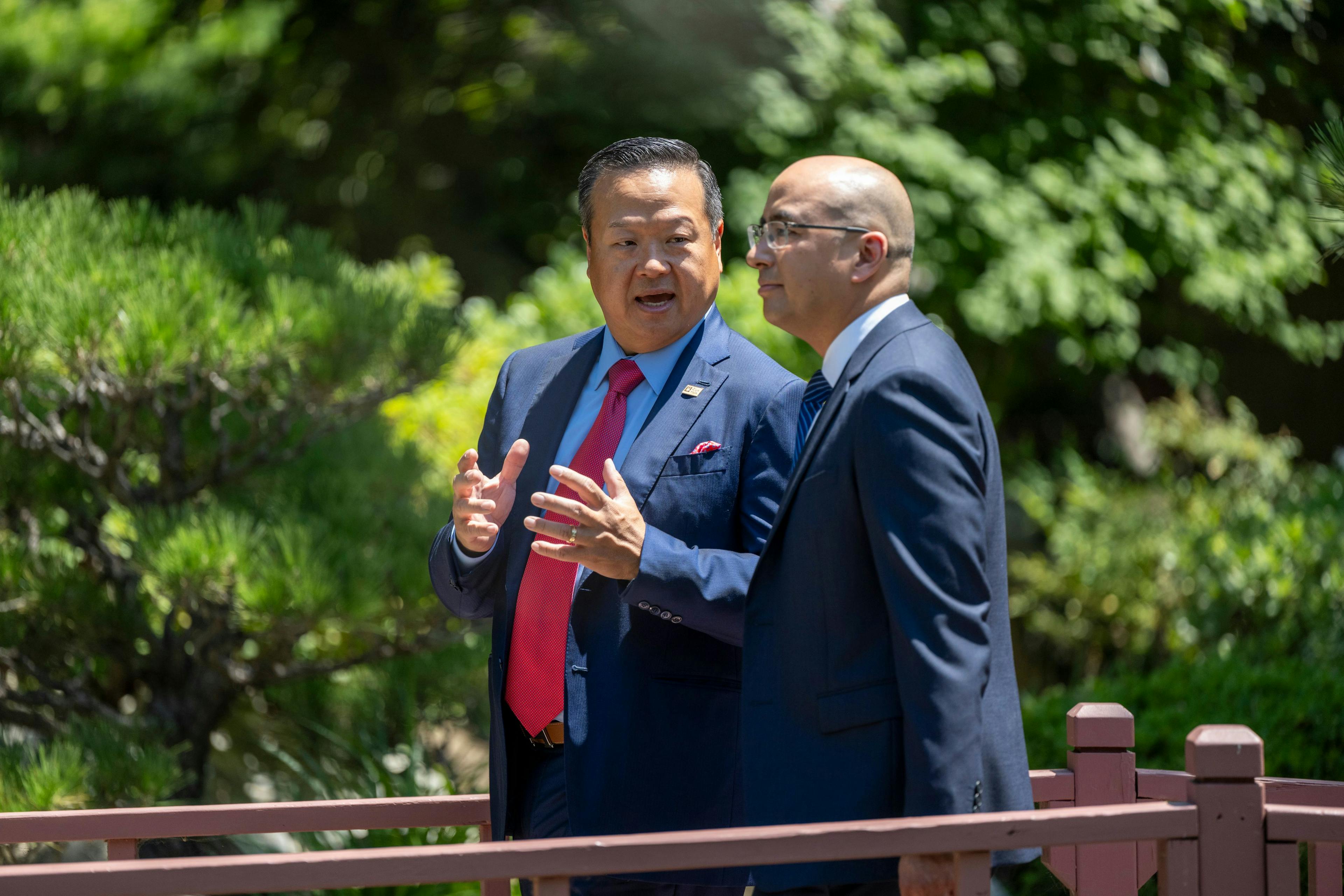 Dr. Richard T. Lee and Dr. Edward Kim talking on a scenic outdoor footbridge