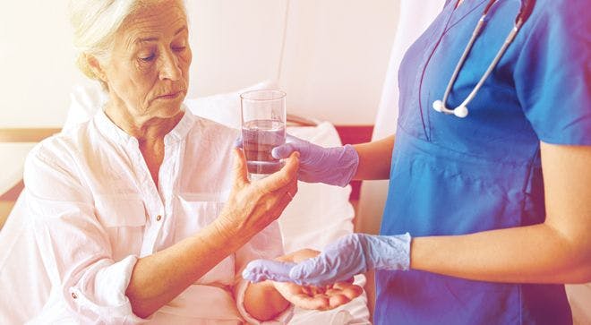 Image of a patient with cancer receiving pills from a nurse.