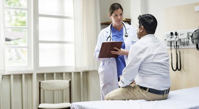 doctor holding a clipboard talking to a patient