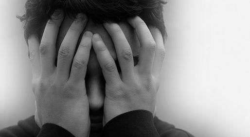 black and white image of stressed person putting their hands on their face