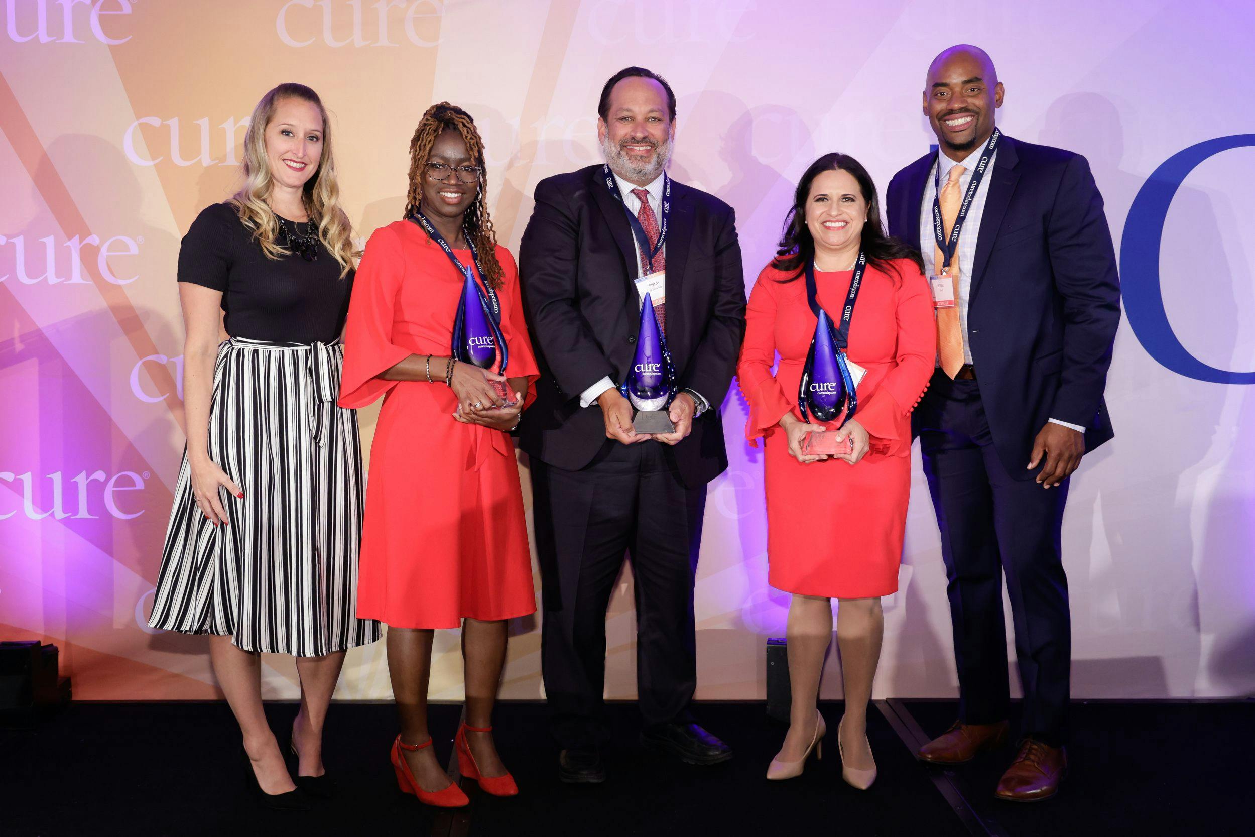 The recipients of CURE®’s third annual Lung Cancer Heroes® awards — Alesha Arnold (second from left), Dr. Pierre de Delva (center) and Dr. Estelamari Rodriguez (second from right) — pose with CURE®’s Vice President of Content, Kristie L. Kahl (left) and keynote speaker Chris Draft (right).