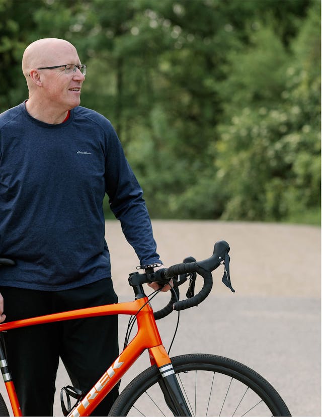 GIST survivor, Lee Keenan, standing with his racing bike. | Photo by Arielle Gallione