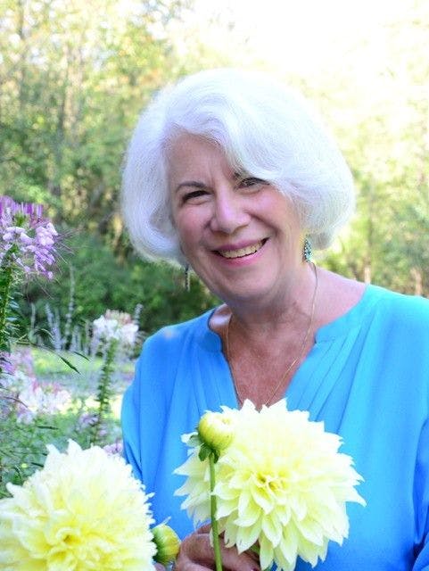 Author and cancer survivor, Charlene Wexler, holding a flower and smiling at the camera