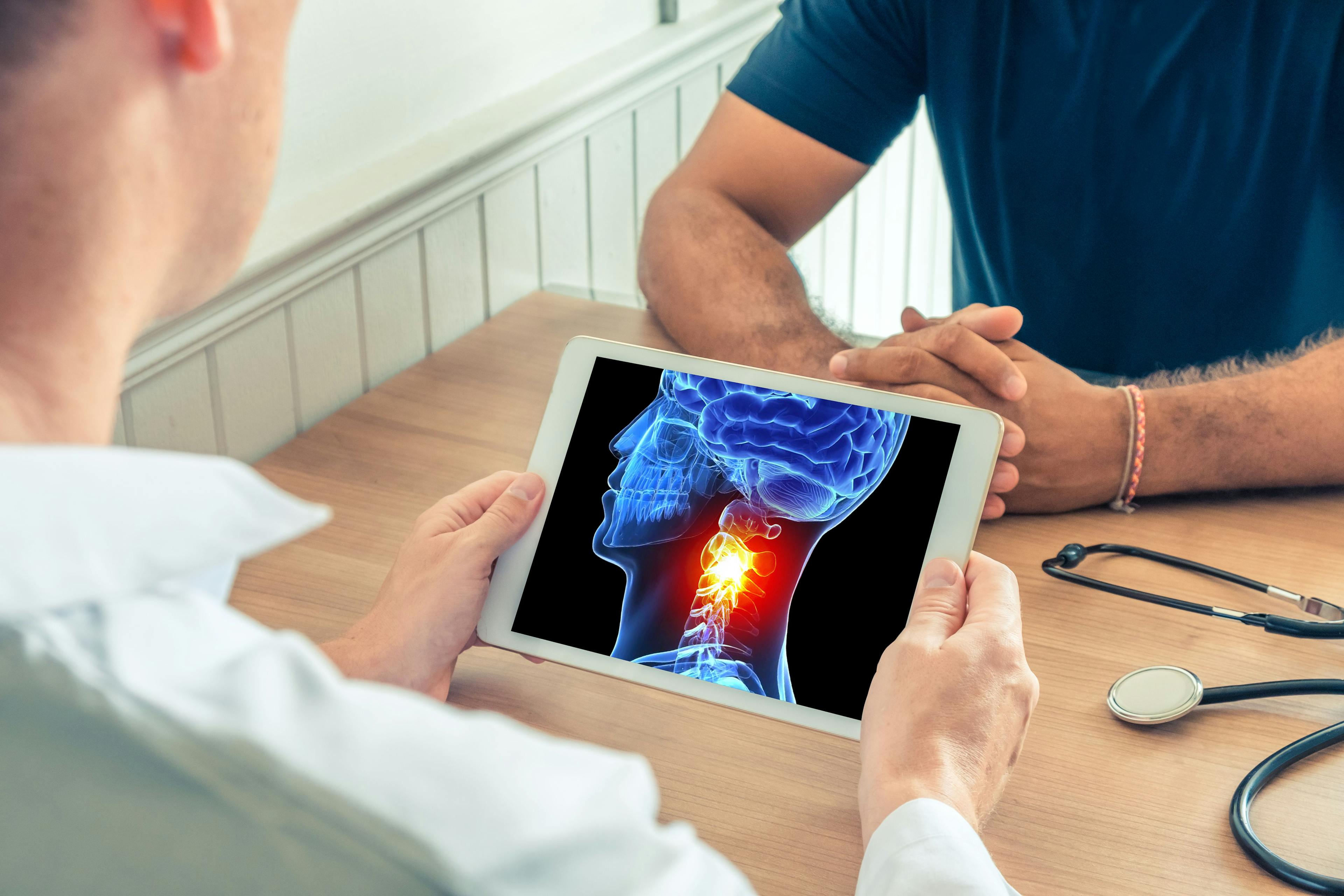 Doctor holding a digital tablet with x-ray of the 3D head of the patient with pain on the neck. Migraine headache concept | Image credit: © steph photographies - © stock.adobe.com