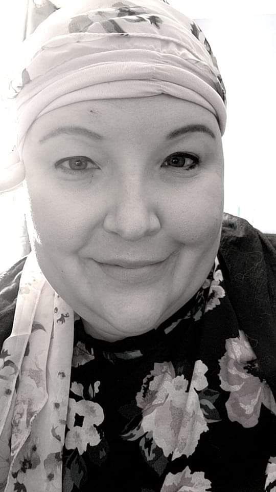 A black-and-white photo of metastatic breast cancer survivor, Elizabeth McSpadden, bald with a headscarf on