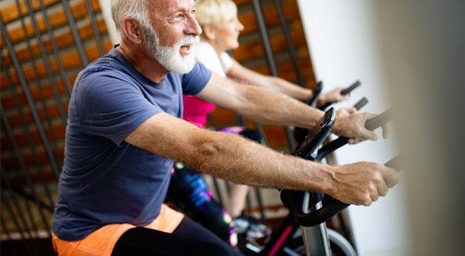 Older man riding a stationary bicycle.