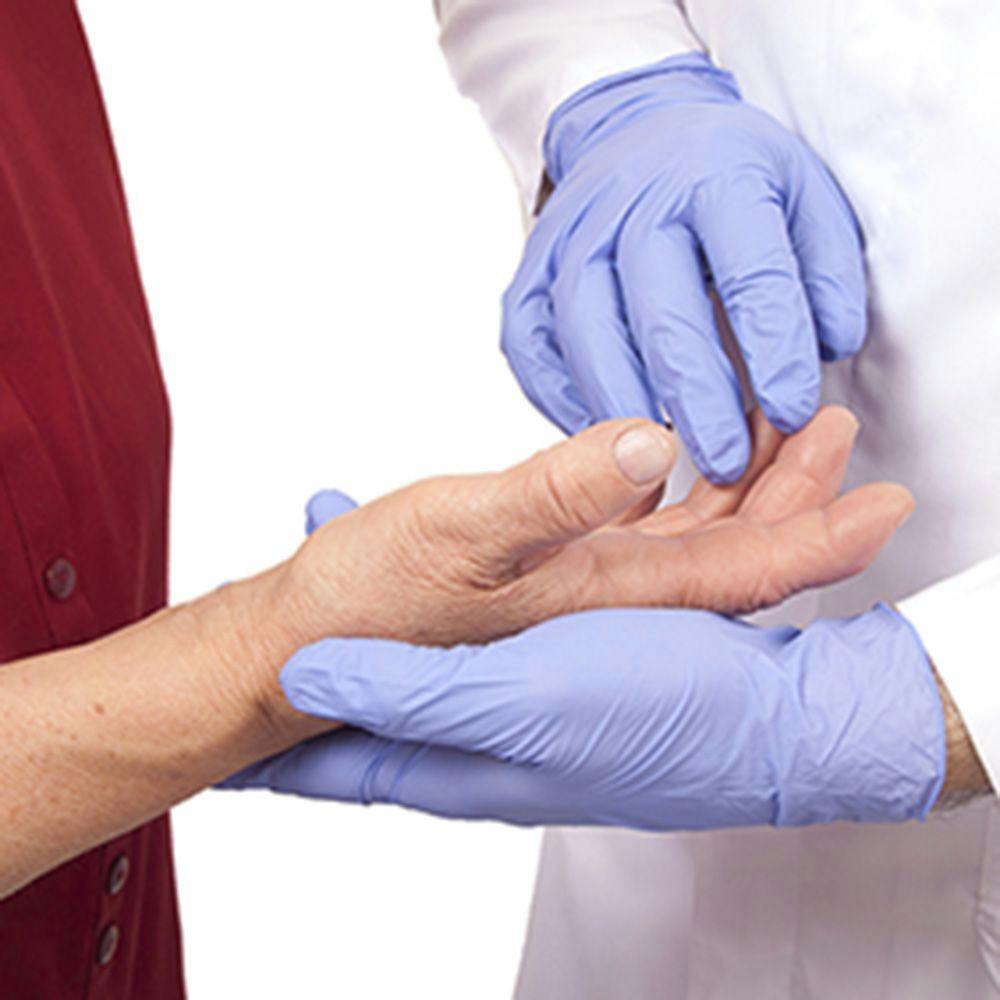 a clinician wearing a white coat and gloves examines the hand of someone experiencing neuropathy